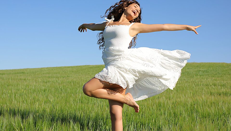 Happy woman twirling with white dress in a field Happy woman twirling with white dress in a field